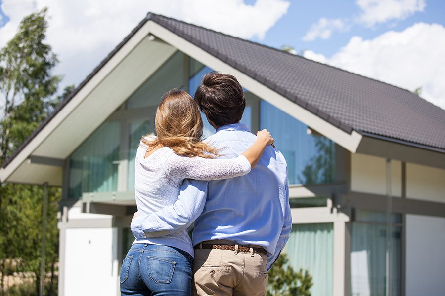 Personal Insurance - Portrait of Couple Facing and Standing in Front of Their Newly Purchased Home if Portland, Maine on a Sunny Day