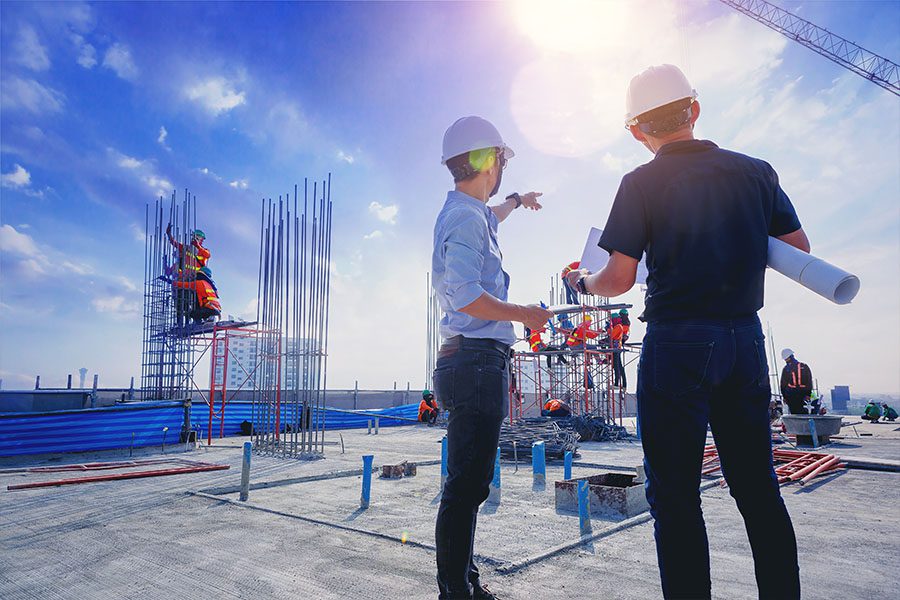 Specialized Commercial Insurance - Business Men Discussing Over Building Designs at a Construction Site on a Sunny Day