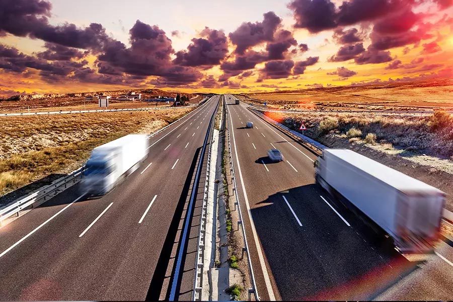 Transportation-Insurance-Blurred-View-of-a-Long-Stretch-of-Highway-with-Trucks-and-Cars-Traveling-in-Both-Directions-at-Dusk